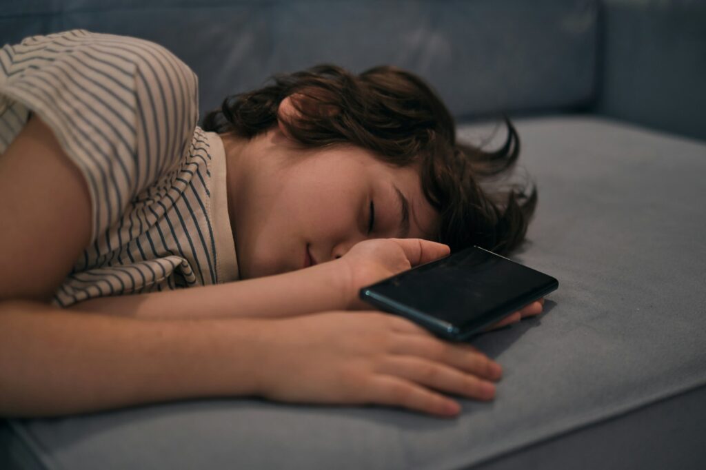 child fell asleep with a cell phone in his arms, on the couch. the impact of gadgets on the