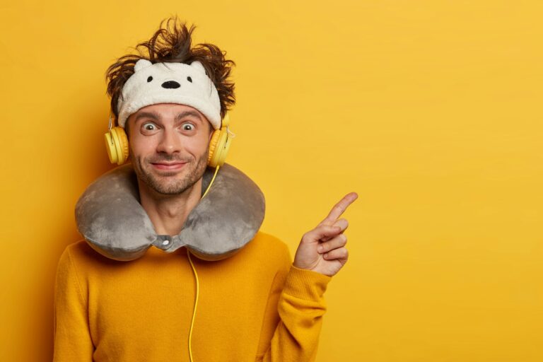 Happy European man points away with fore finger, listens favourite music via headphones, flies in ai