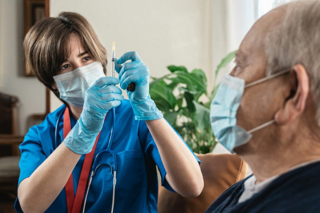 Nurse doctor giving senior patient a vaccine for coronavirus disease while at home