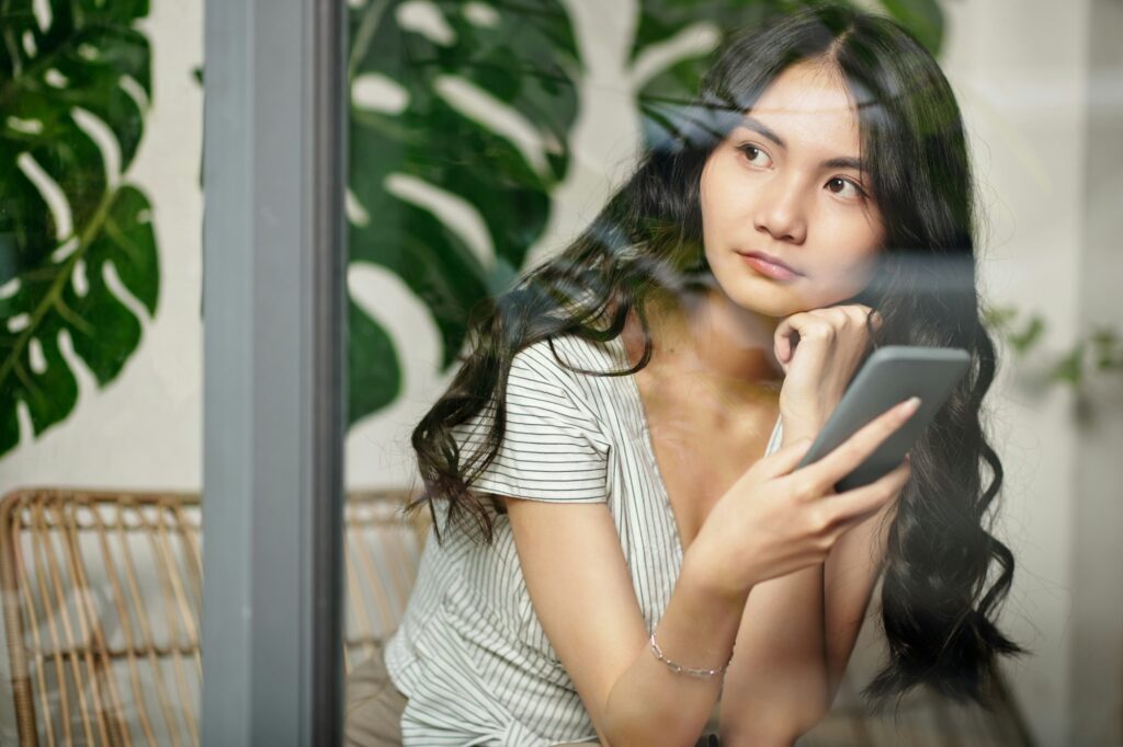 Pensive Young Woman with Smartphone