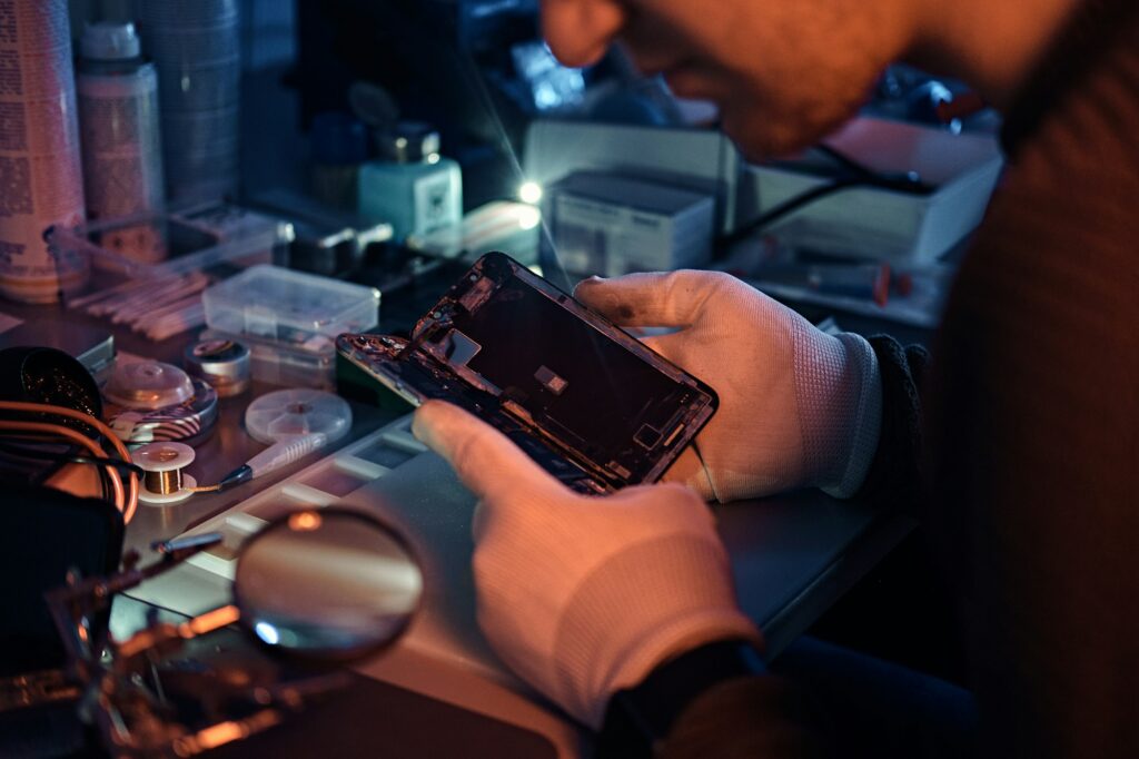 Technician carefully inspect the internal parts of the smartphone in a modern repair shop