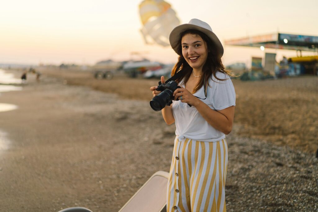 Traveling and photography. Young woman with a camera is photographed on the sea beach.