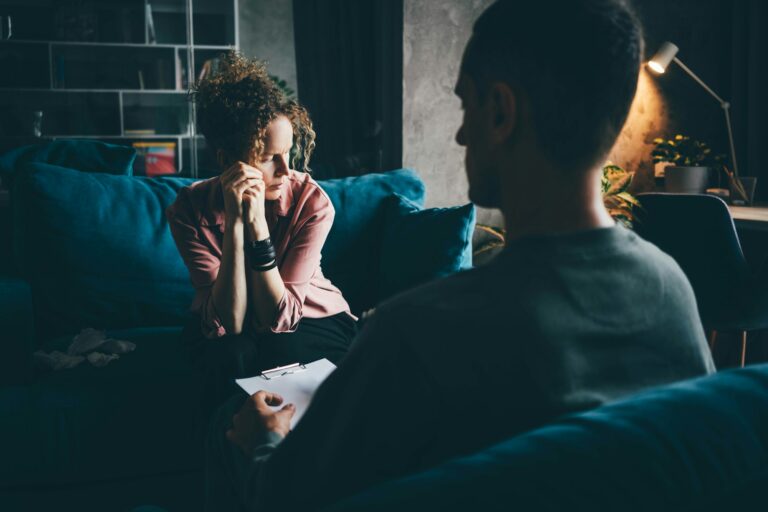 woman in pink blouse gets emotional support from professional psychologist sitting on sofa