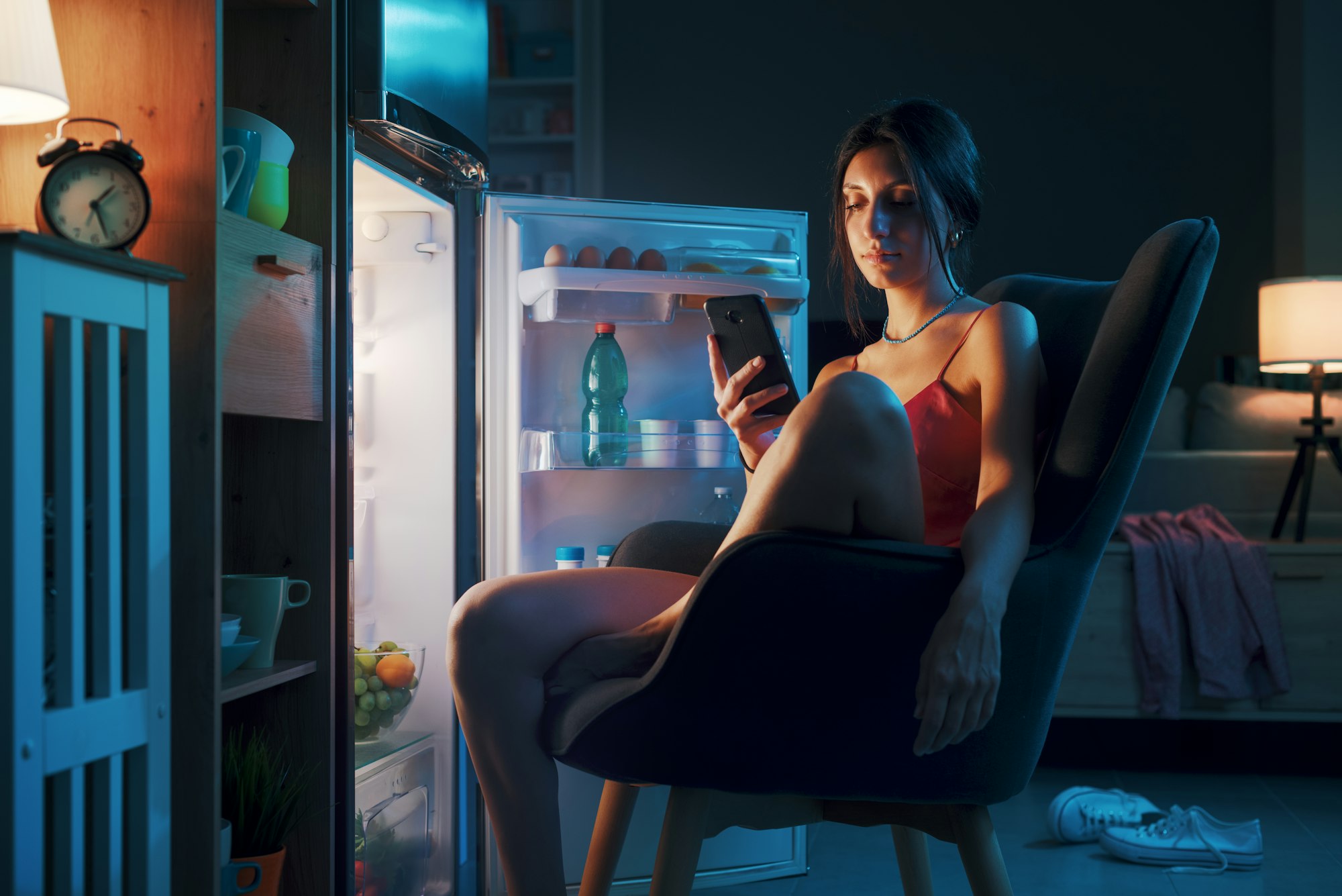 Woman suffering from the heat and sitting in front of the open fridge