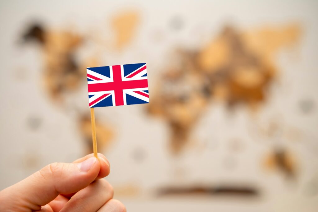 British flag in mans hand on the world map background.