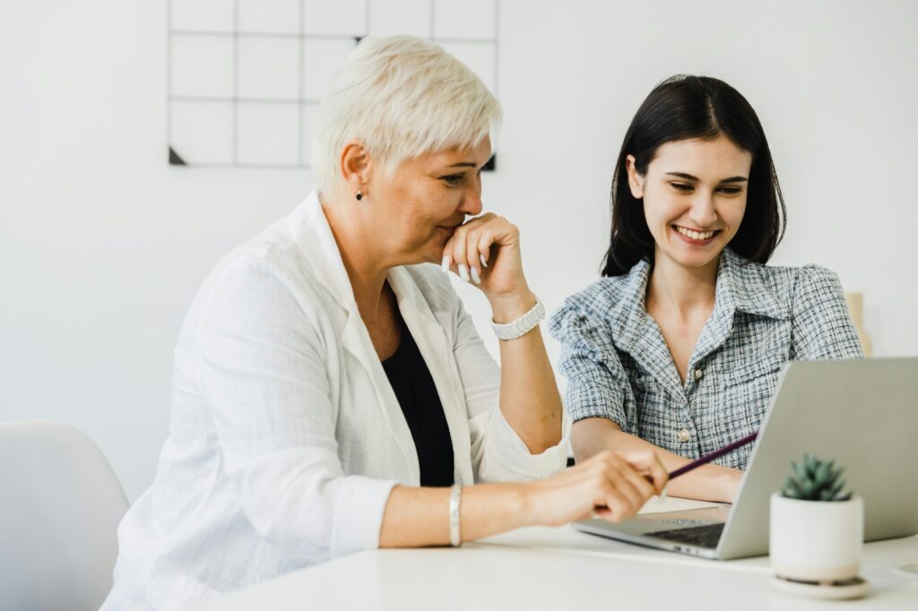 Happy senior old businesspeople discussing with worker online project on laptop