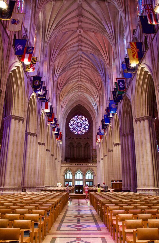 Looking down rows of empty chairs toward the pulpit of a nearly empty cathedral