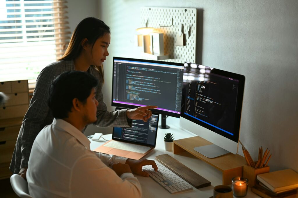 Male and female software developers sharing idea and discussing algorithms on computer screens