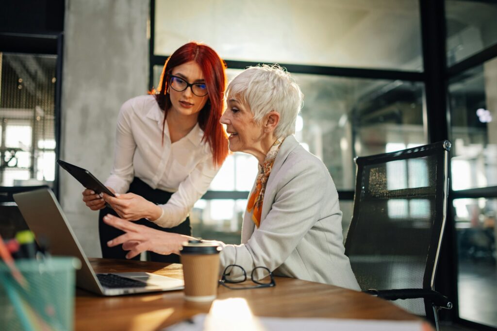 Old female executive discussing paperwork with her worker at office.