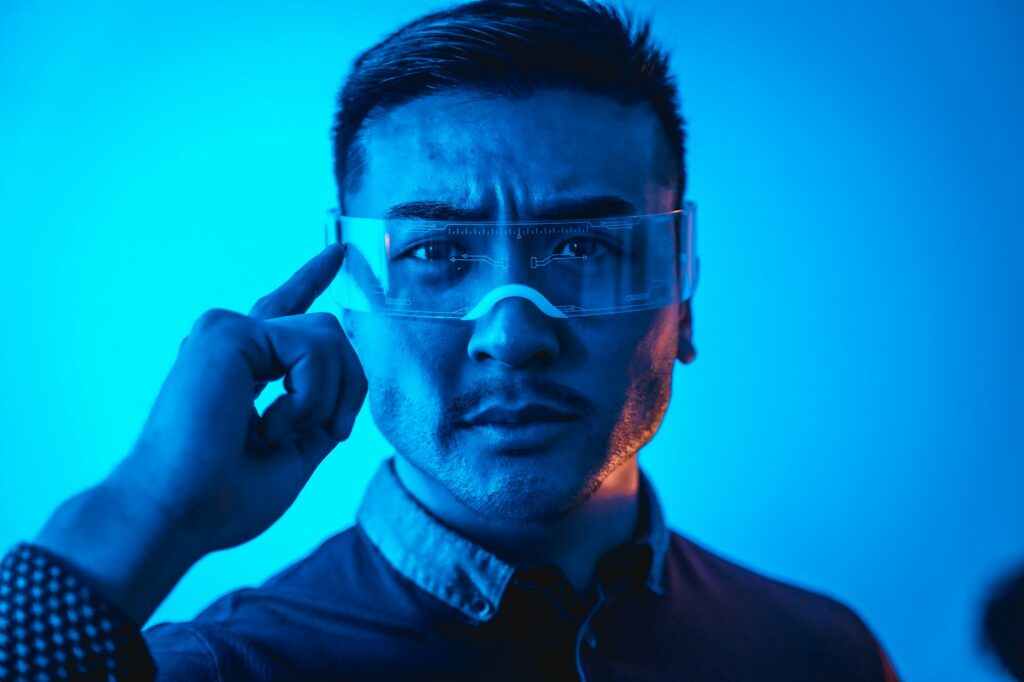 Portrait of young chinese man with neon glasses with a blue light, futuristic concept, technology