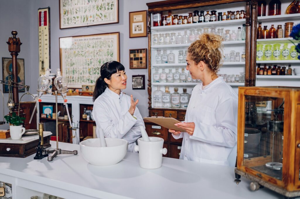 A Japanese pharmacist is teaching her assistant traditional medicine while standing in an apothecary