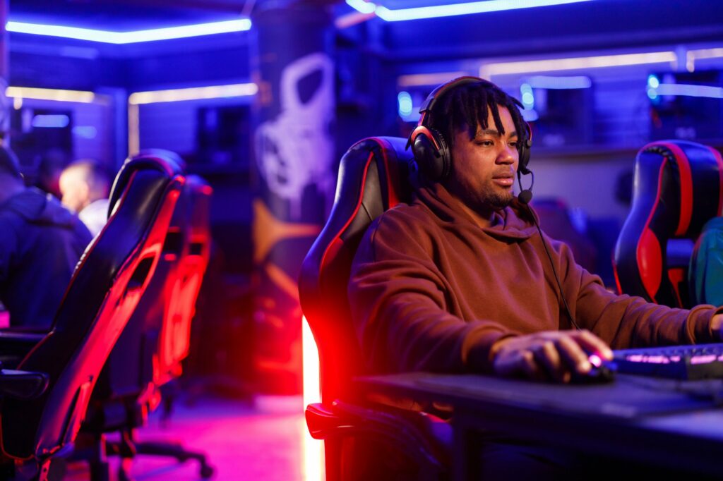 African american man with dreadlocks playing a video game in a gaming lounge