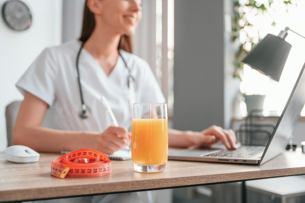 Apple juice and measuring length is on the table. Young beautiful female doctor