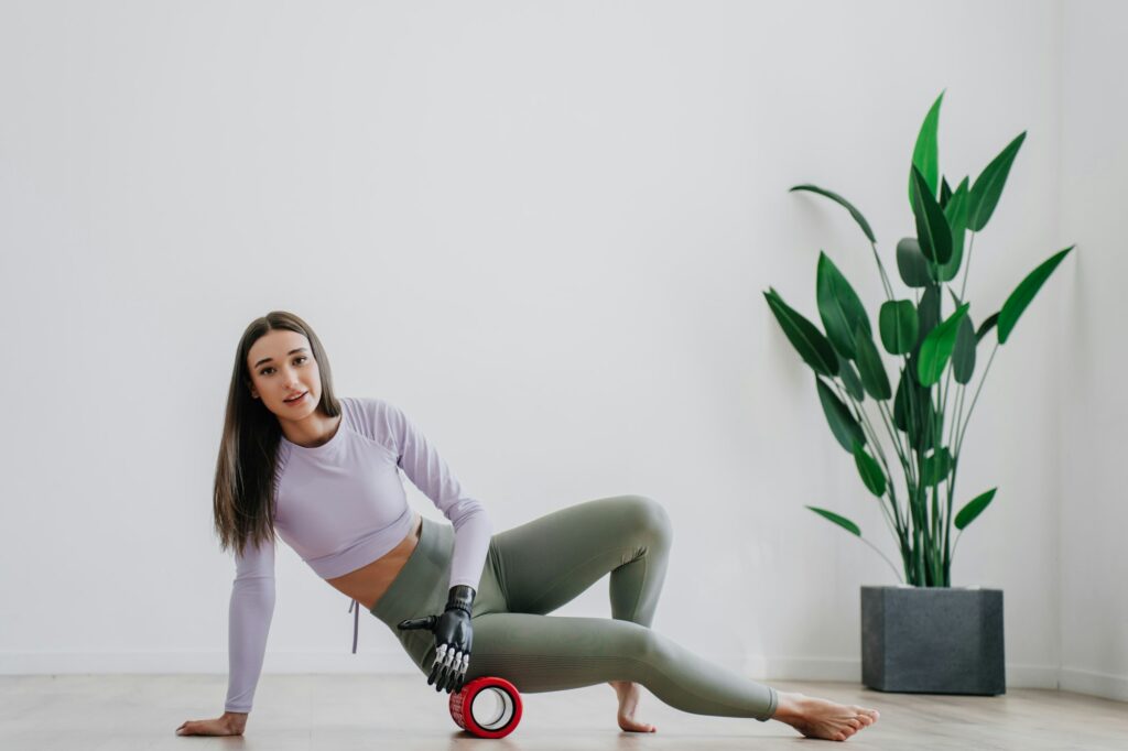 brunette European girl in sportswear makes exercise home massaging roll by bionic arm prosthesis