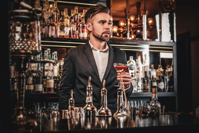 Elegant groomed man is drinking alcohol at the bar