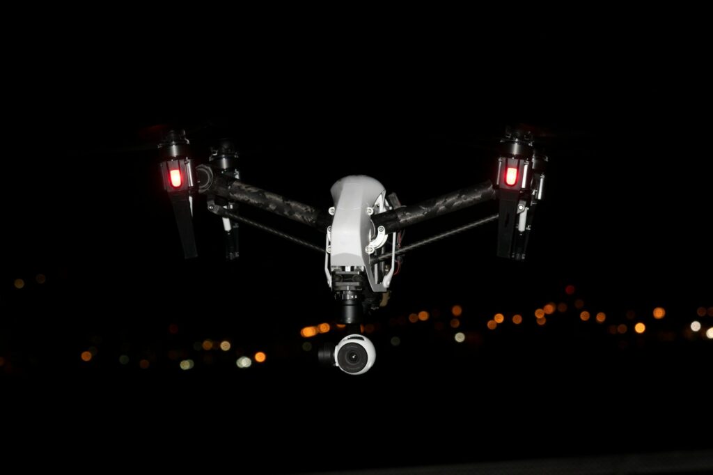 Futuristic flying camera drone in action at night.