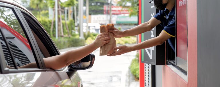 Hand Man in car receiving coffee in drive thru fast food restaurant.