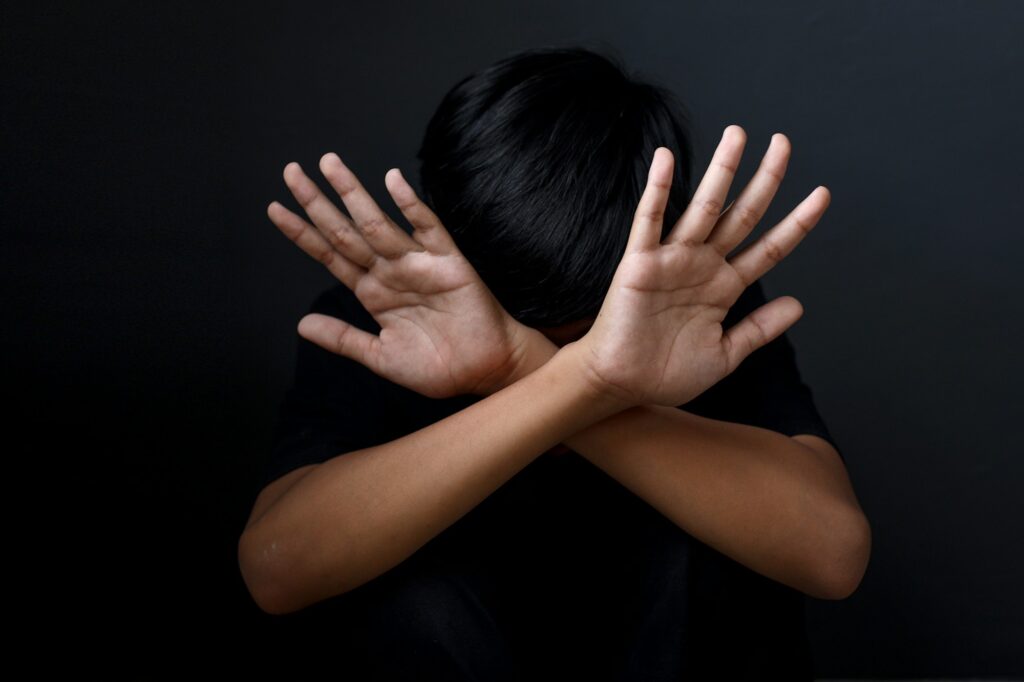 Kid showing hands doing stop gesture, stopping violence against children.