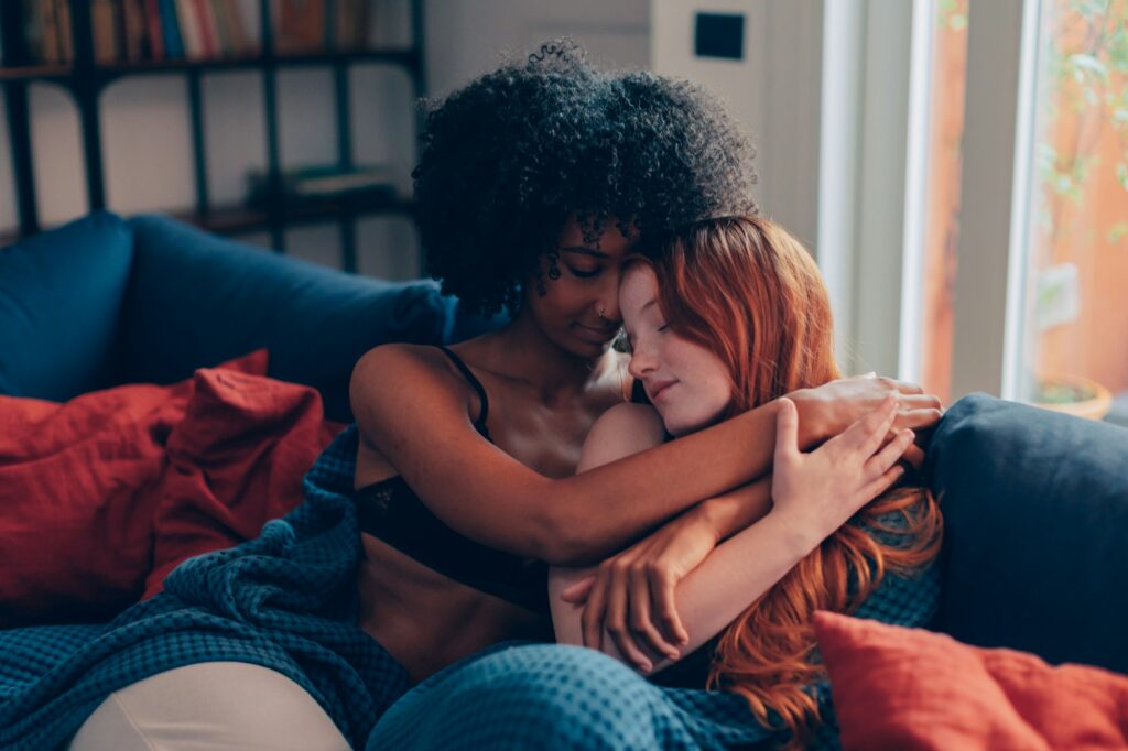 multiracial women in love embracing in the privacy of their apartment