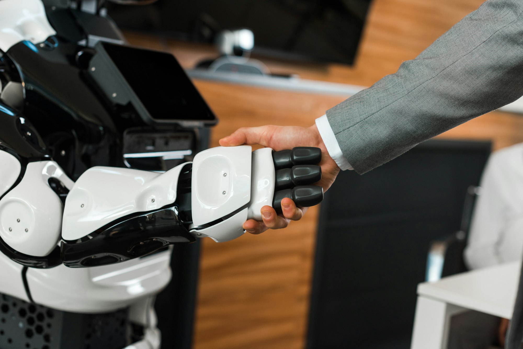 partial view of businessman shaking hands with humanoid robot in office