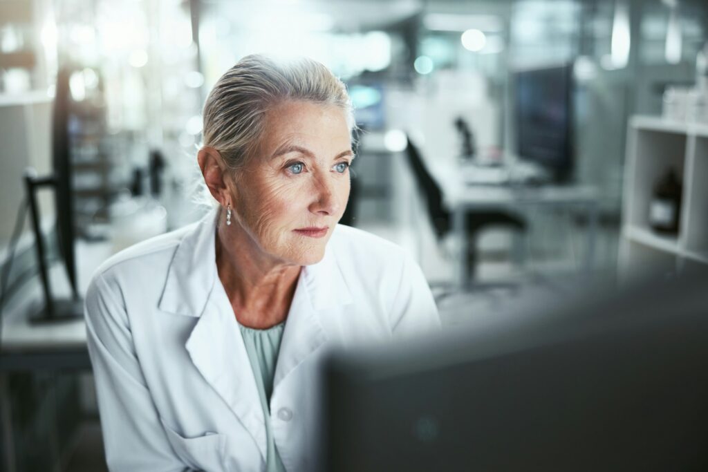 Reading, woman and scientist with computer in laboratory for medical research on cancer drug trial.