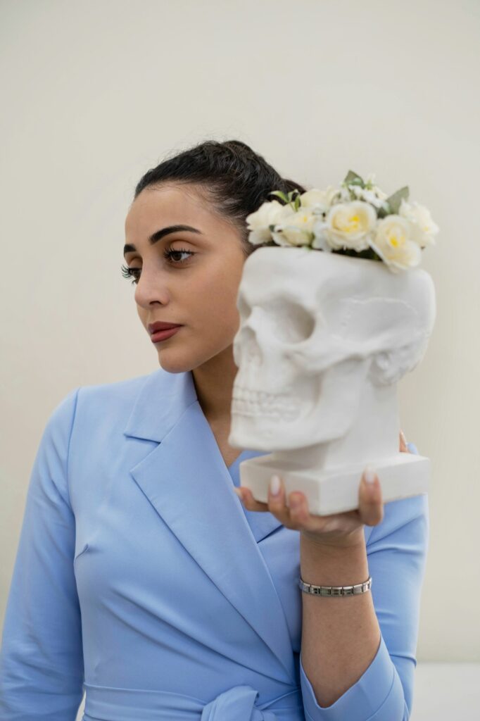 Woman in a blue scrub holds a decorated skull, blending the artistic with the anatomical