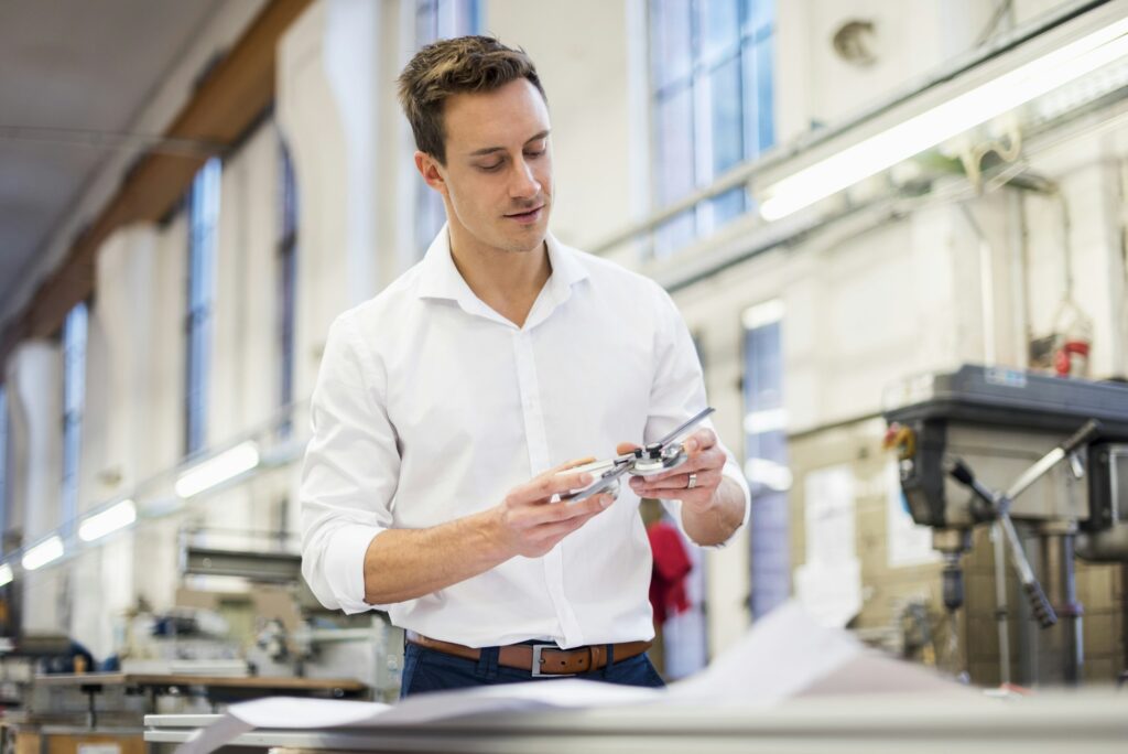 Young businessman in factory holding component