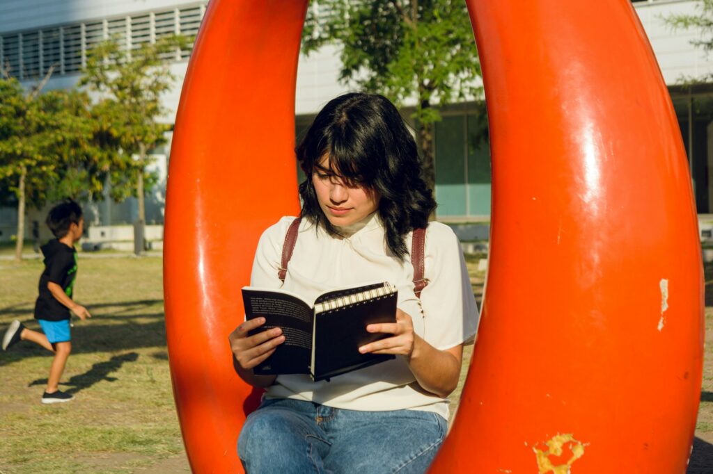 young latin woman sitting in a park concentrated reading a book.