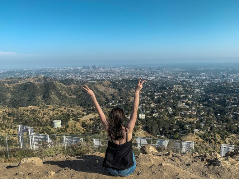 Young woman sitting behind the Hollywood sign overlooking Los Angeles