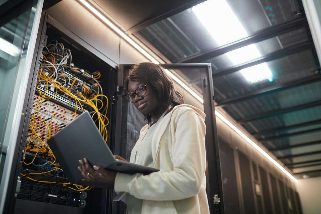 African American Woman Inspecting Servers in Data Center