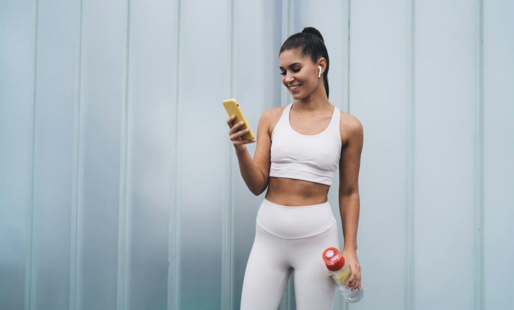 Attractive brunette woman with fit figure controls physical activity using mobile app