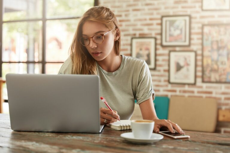 Focused pretty female model dressed in casul t shirt, watches attentively training video on laptop c