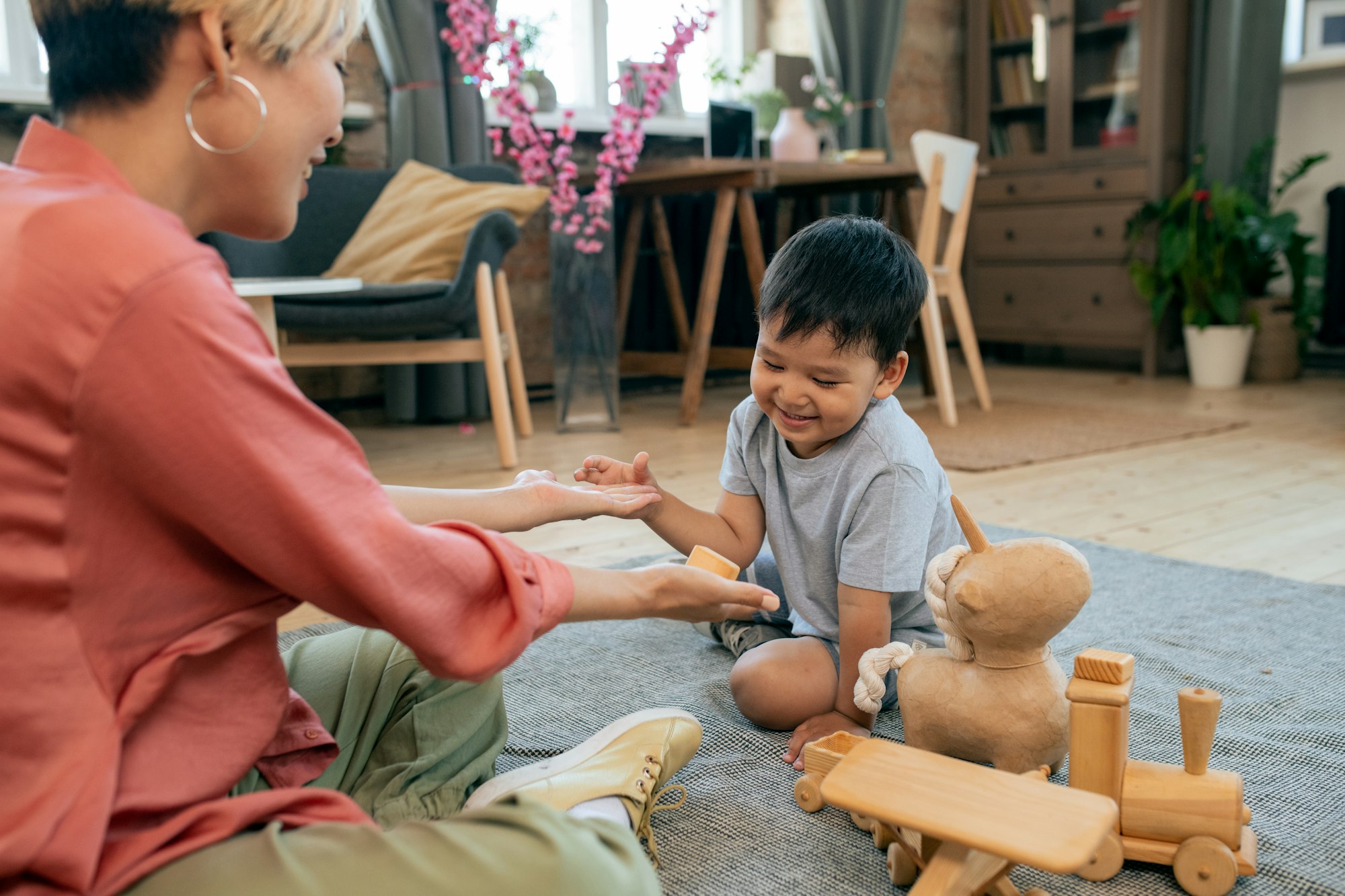 Happy young woman showing new toy to cute little son