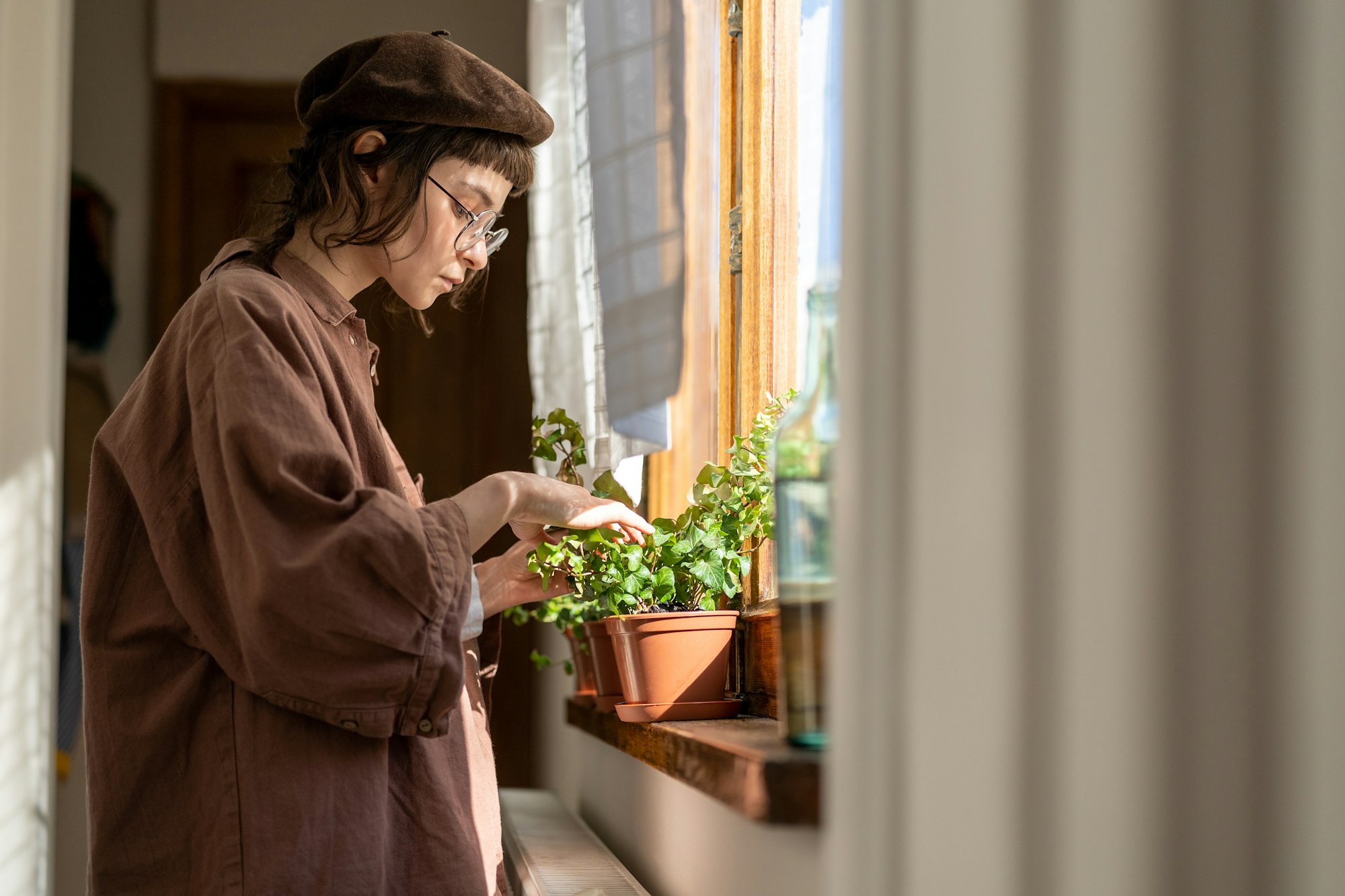 Hipster girl taking care of houseplants, checking if plant is healthy. Plant lovers.