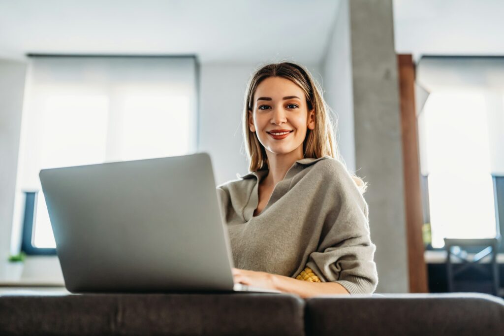 Home office. One smiling woman using laptop. Work, freelance, social media, technology concept.