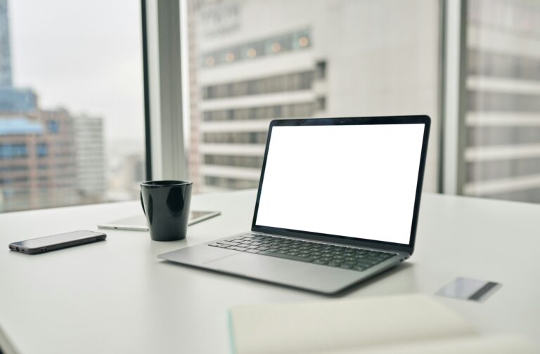 Laptop computer with white mock up empty blank screen on desk in office.