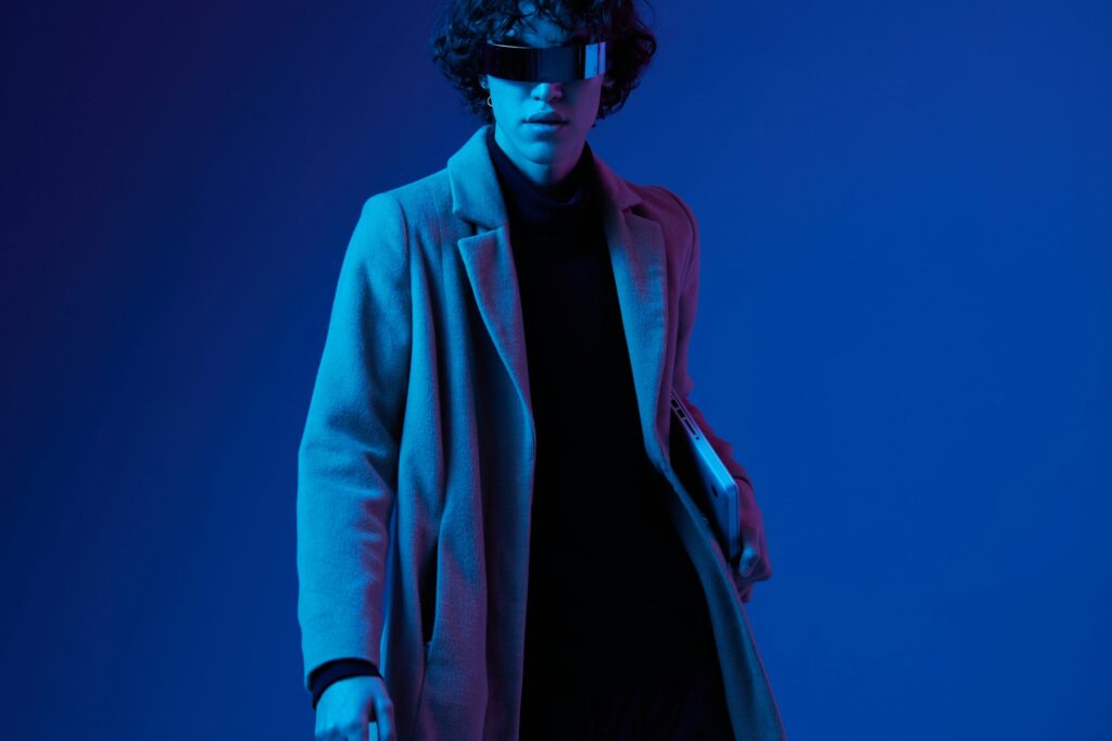 Male hacker with a laptop in his hands and a jacket, futuristic glasses in blue light, Blue