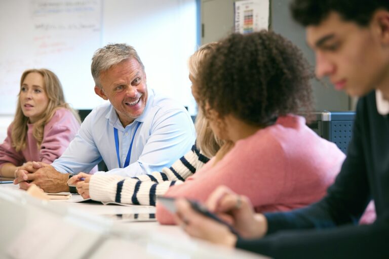 Male Tutor In Science Classroom Teaching Group Of College Or University Engineering Students