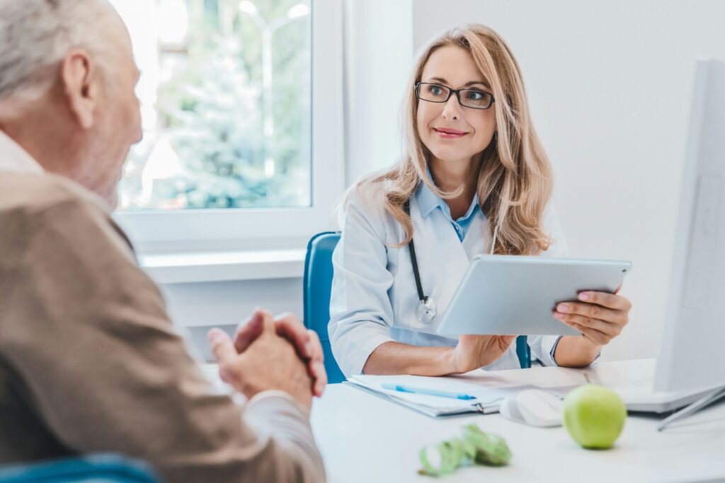 Middle aged female doctor nutritionist in white medical coat consulting her old patient