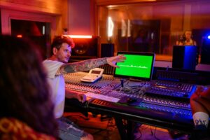 Music technician raised hand during recording of a vocal track in music studio.