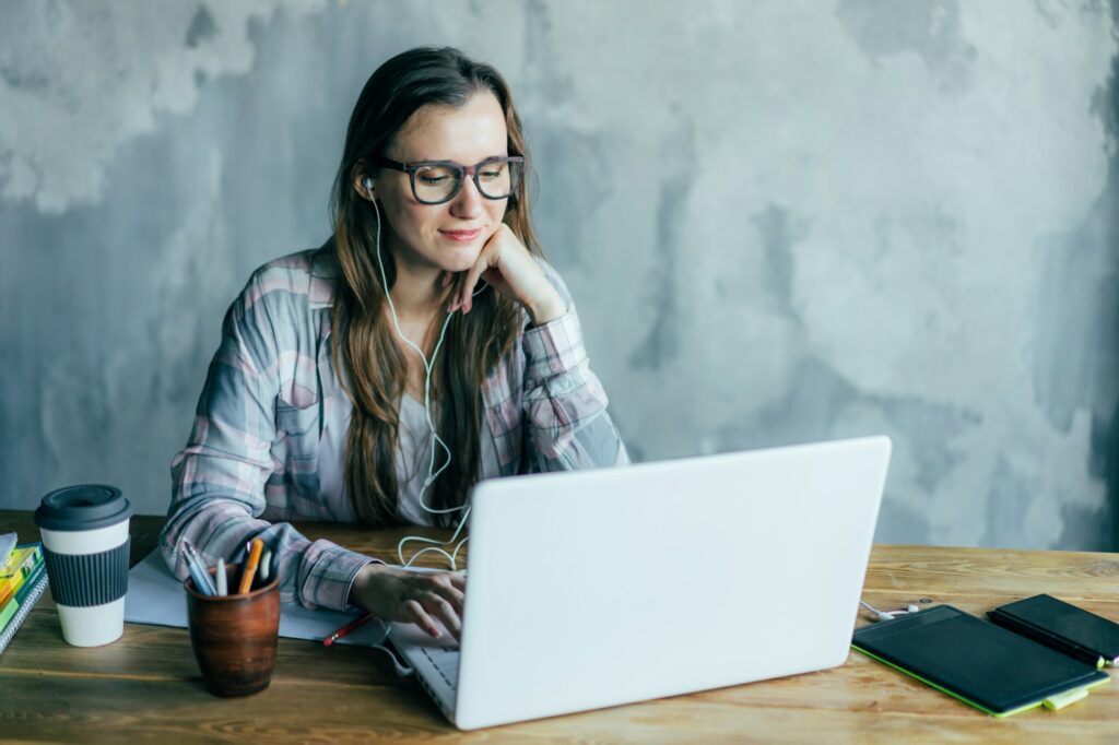 The student sits with a laptop at the table. Educational process, lectures and homework. Online educ