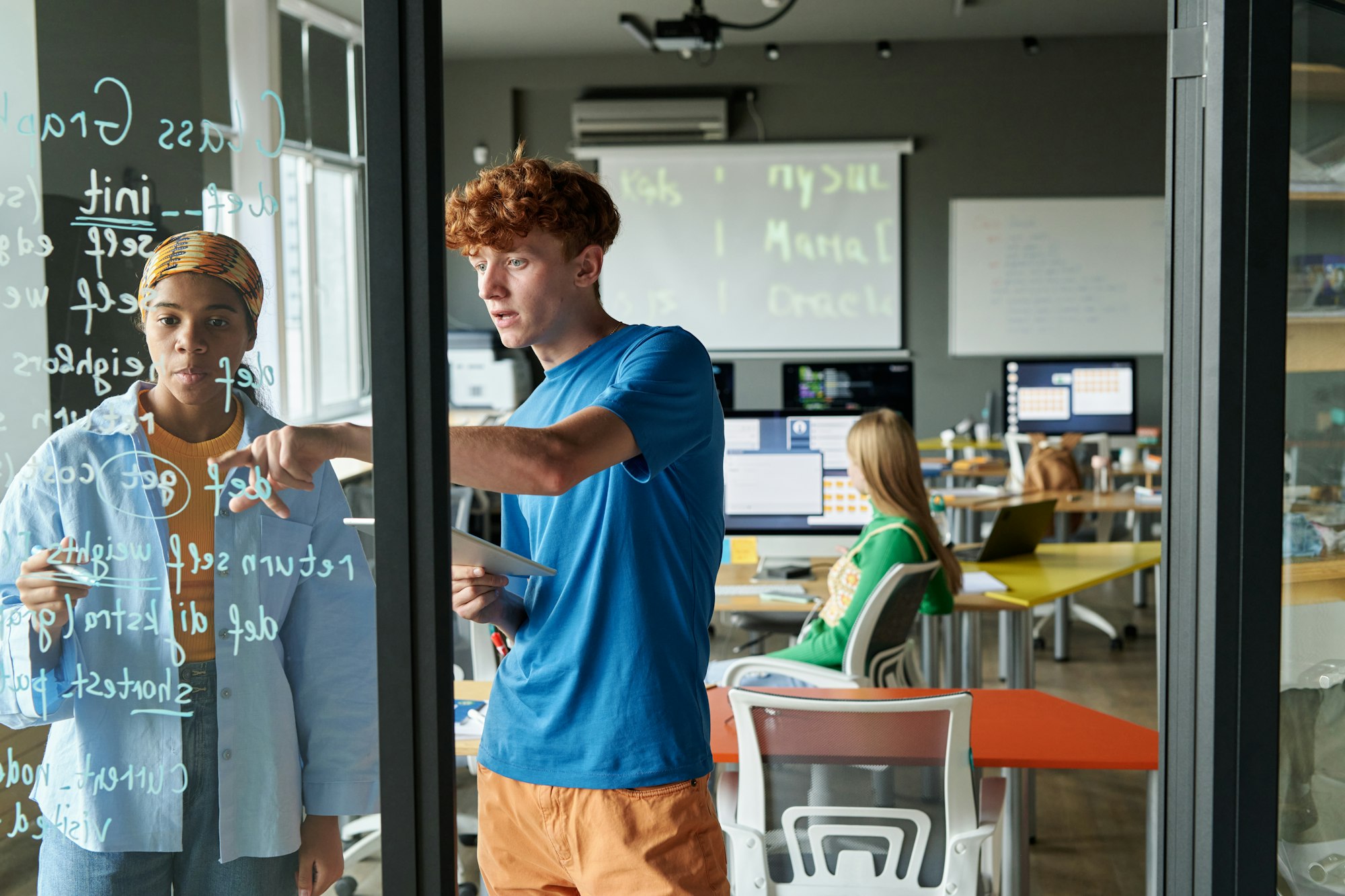 Two People writing Formulas on Glass Wall in School