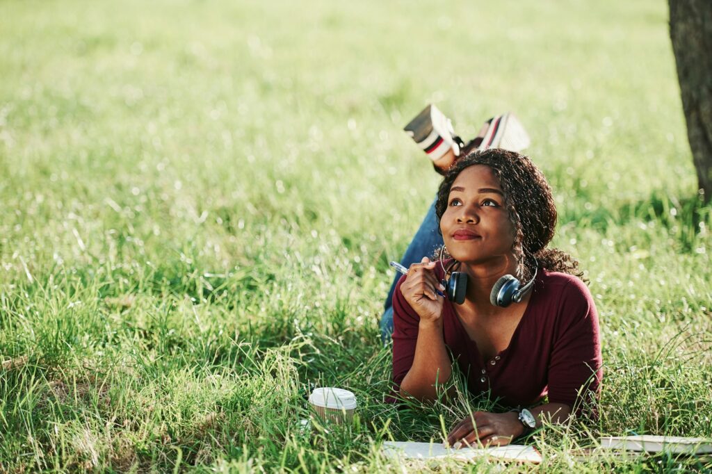 Writer thinks how to finish the chapter. Cheerful african american woman in the park at summertime