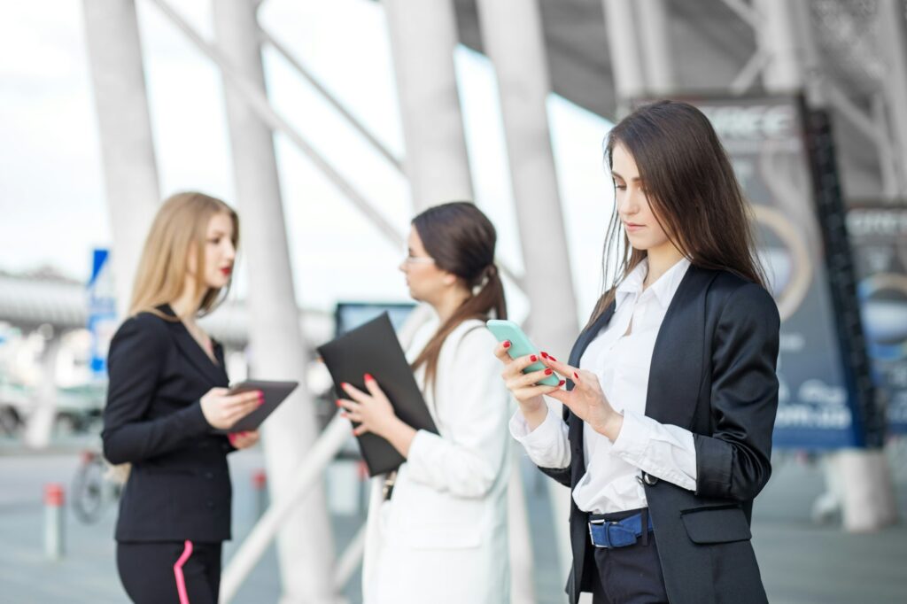 Young female boss reads messages on an android near a business center.