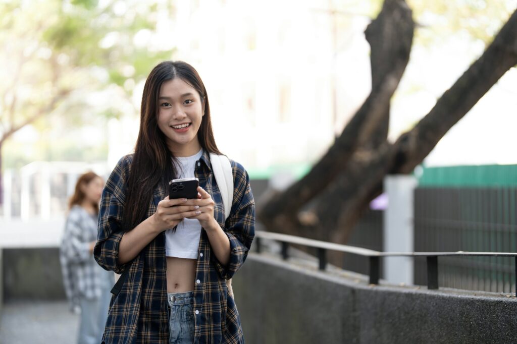 young happy attractive asian student smiling and looking at camera with friends on outdoor