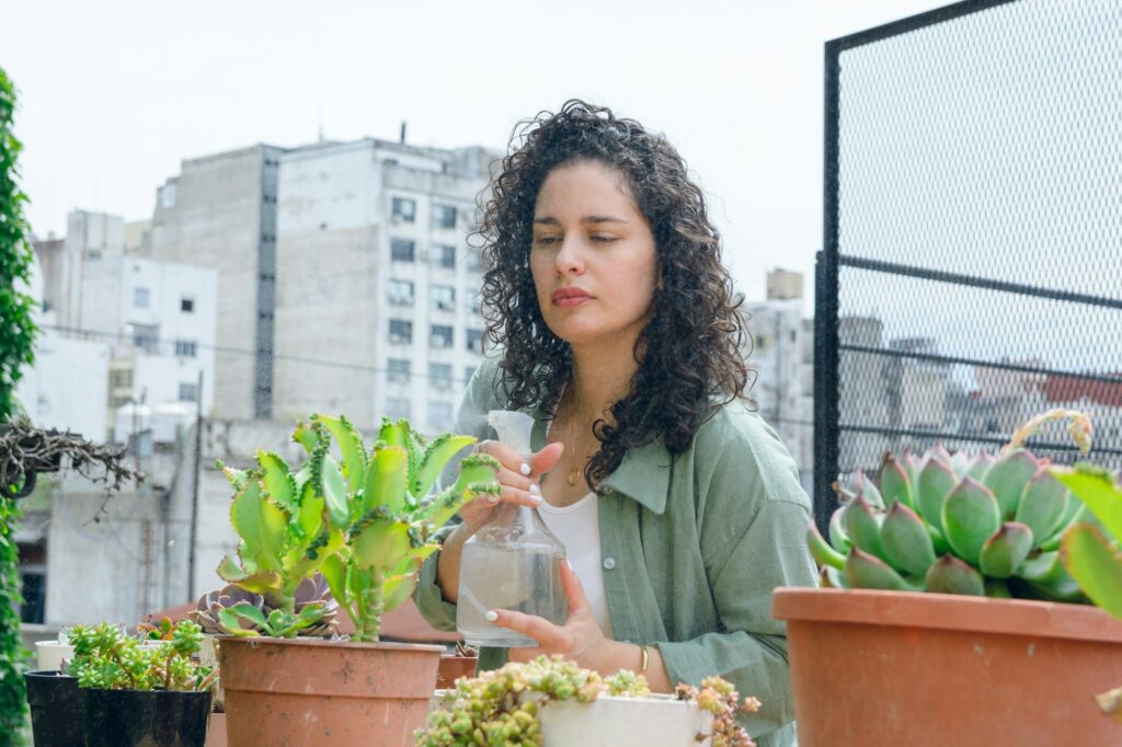 young latin woman working doing maintenance to plants on terrace