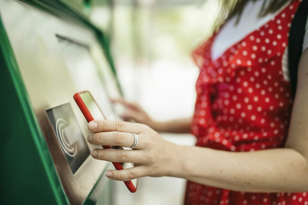 Young woman paying with mobile phone app for the public transport