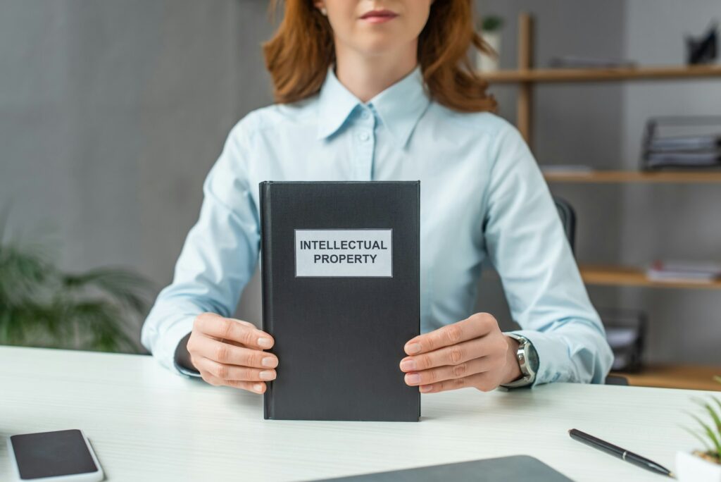 Cropped view of female lawyer showing book with intellectual property lettering, while sitting at