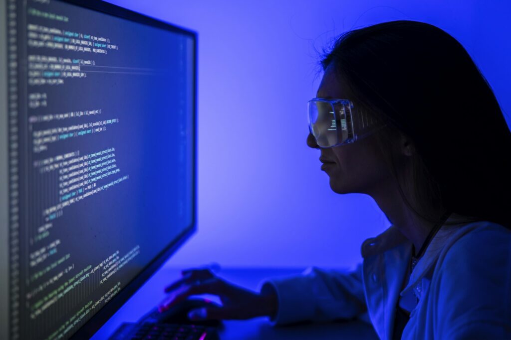 Female Software Developer Concentrating on Coding Project at Workplace During Nighttime