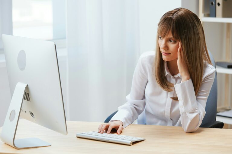 Focused adorable blonde businesswoman typing answer for client look at screen sitting at workplace